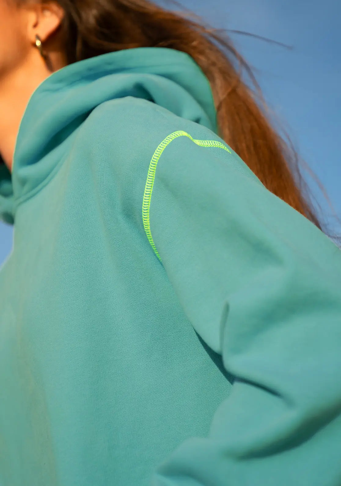 Hoodie Lagoon color verde agua y amarillo flúor. Detalle de costuras en el hombro.
