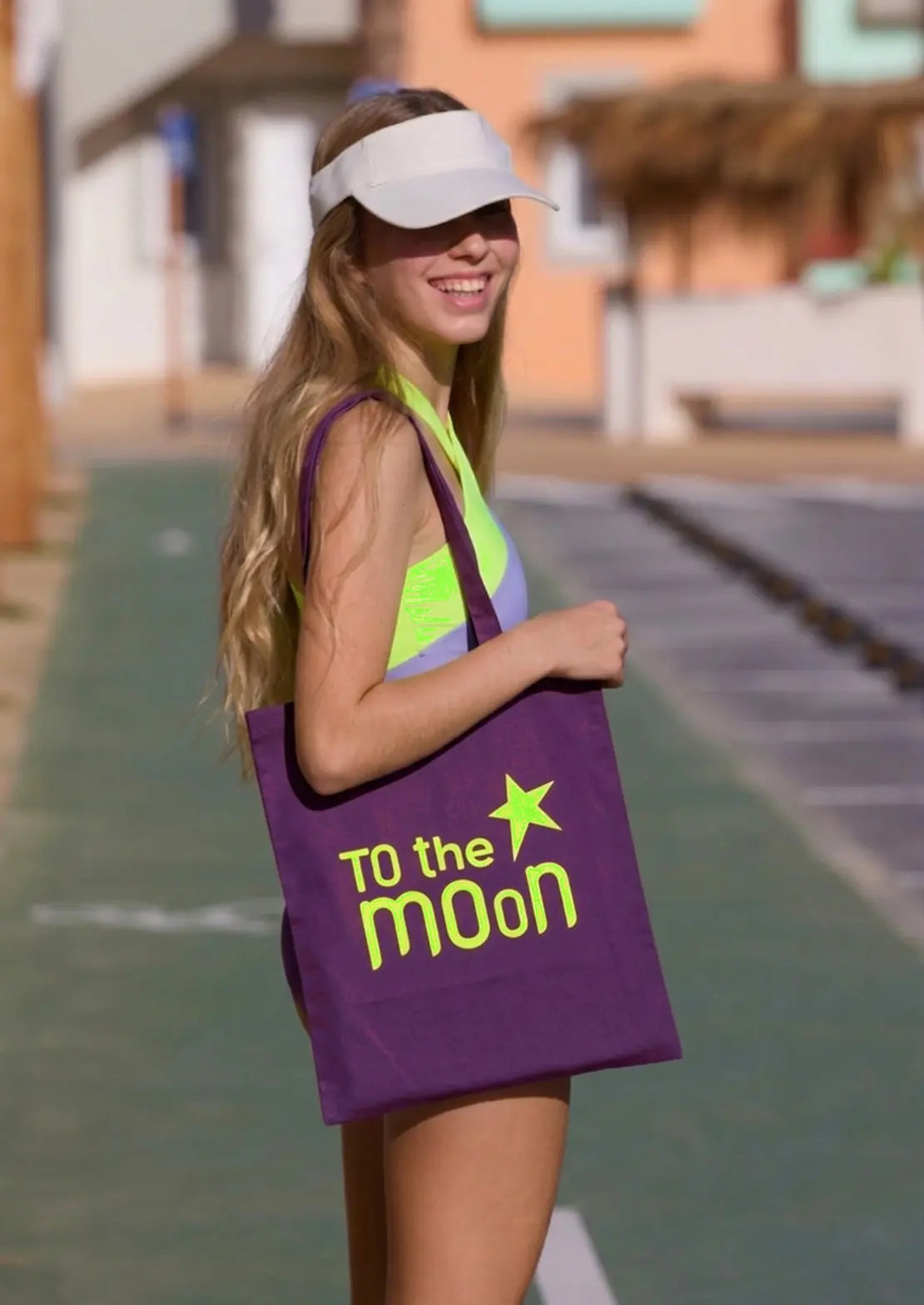 Teen con tote Bag morada con logo en amarillo neón de To the Moon.