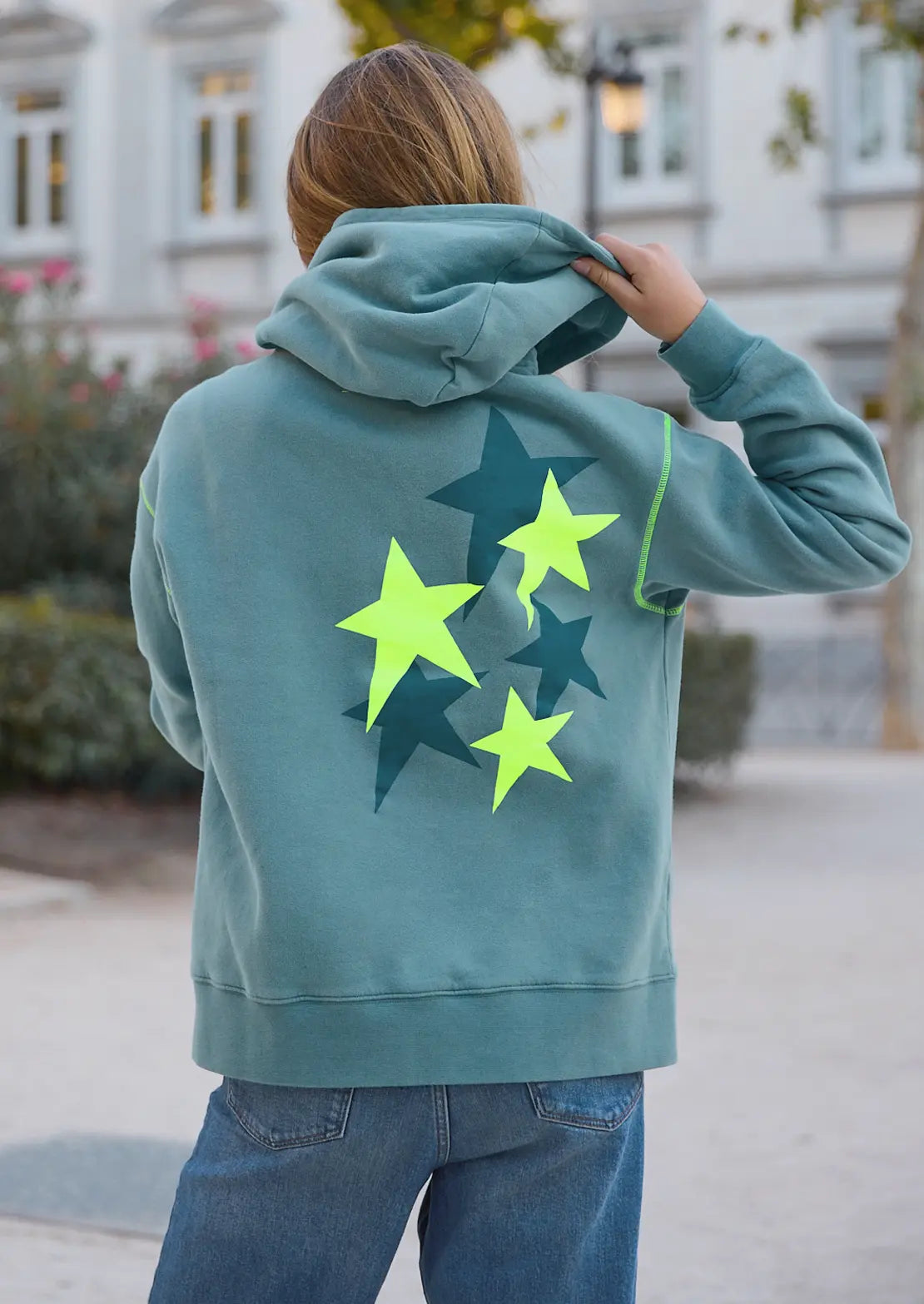 La sudadera cosmos Ocean de la temporada con capucha y bolsillo canguro de To the Moon. Serigrafía amarillo neón y verde de estrellas en la espalda y bordado de marca en parte delantera.