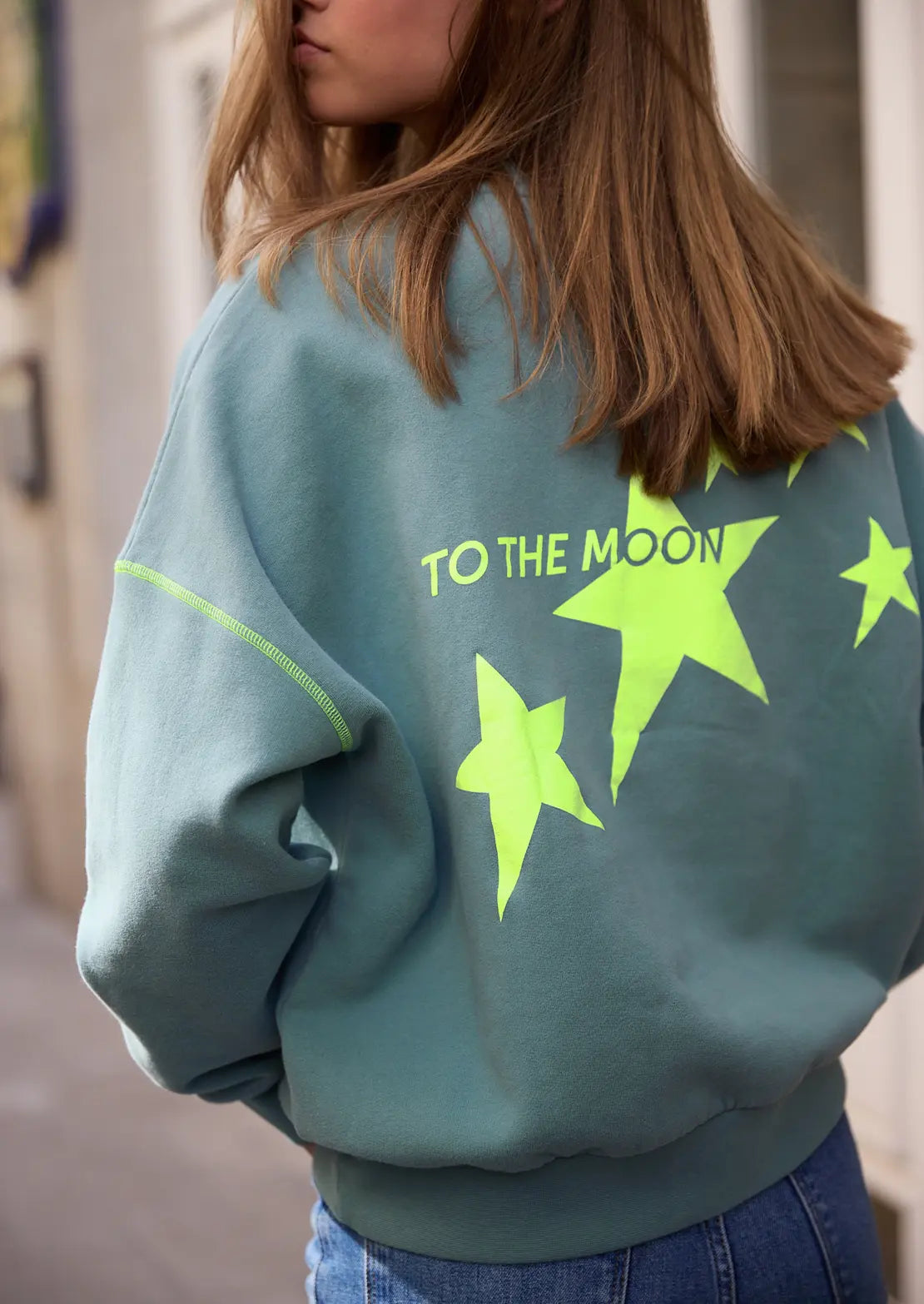 Sudadera de To the Moon en color azul petróleo manga caída ideal para teens. Bordado delantero y serigrafía trasera y costuras en amarillo flúor.