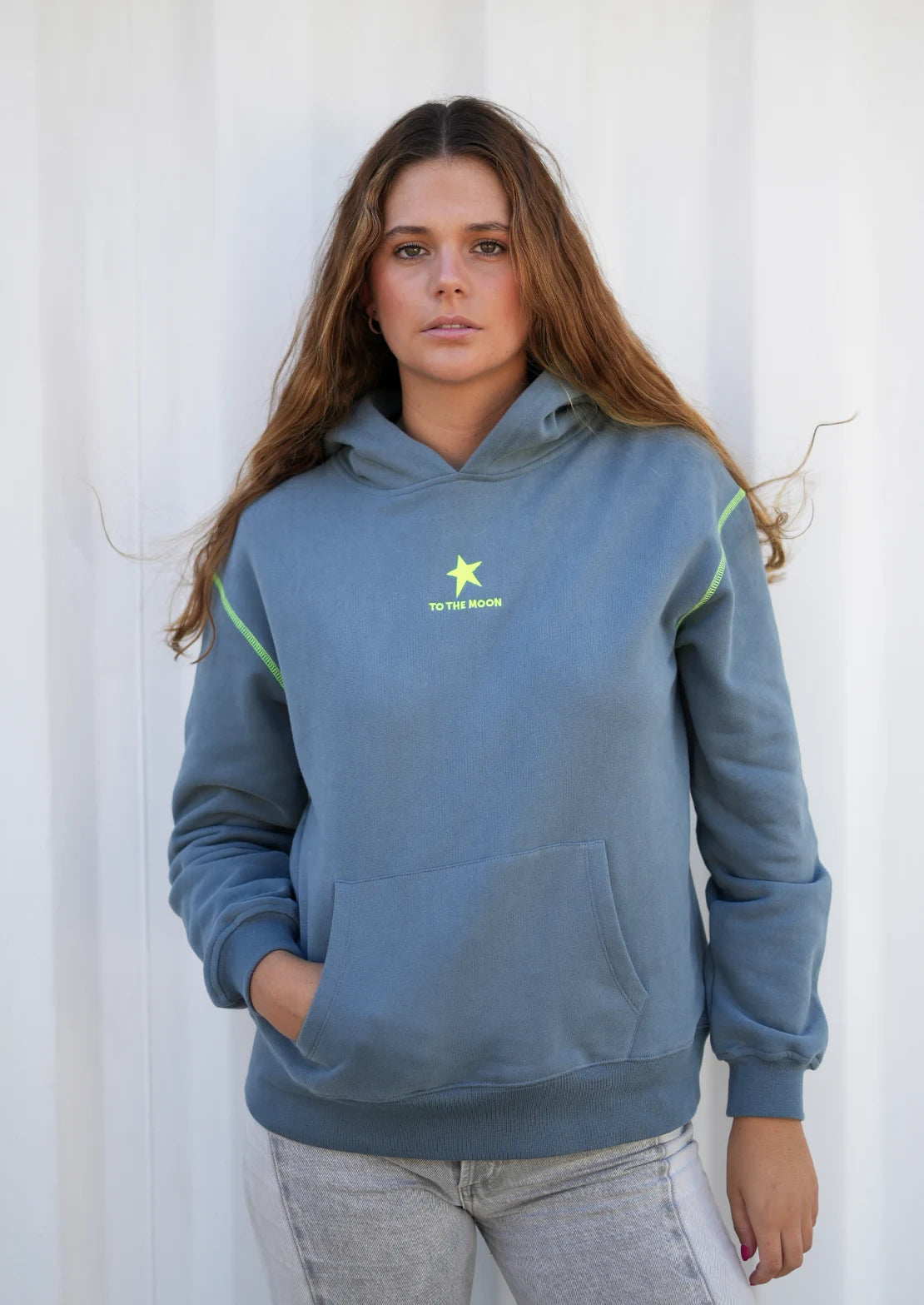 Sudadera con capucha y bolsillo canguro de To the Moon en color gris. SerigrafĂa trasera amarillo flĂșor con estrella y frase "Chasing Stars Daily".