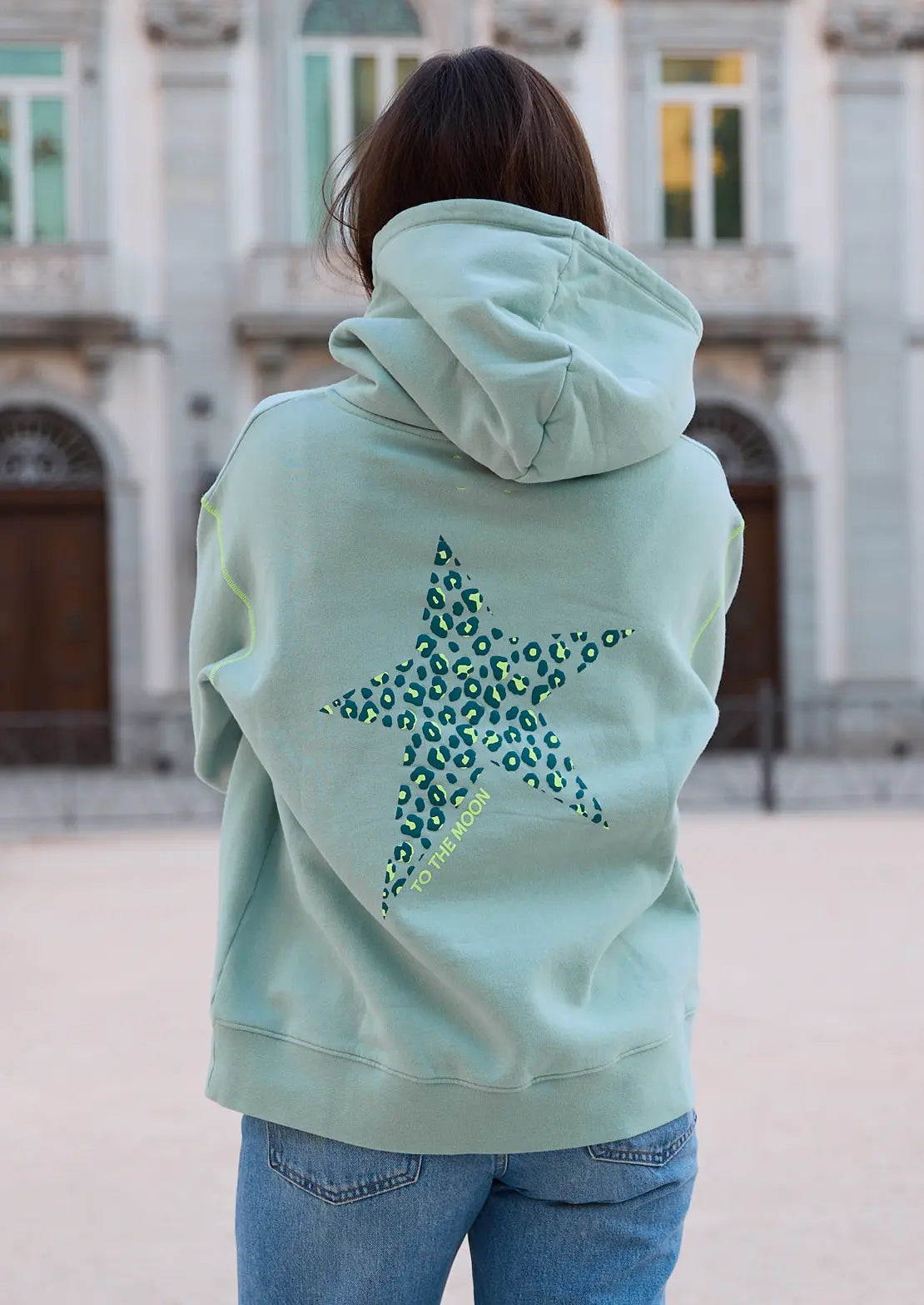 Hoodie de To the Moon en color verde claro con capucha y bolsillo canguro. Serigrafía amarillo neón en la espalda estrella leopardo.