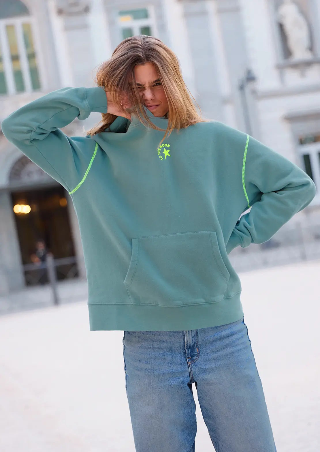Hoodie de To the Moon en color azul petroleo con capucha y bolsillo canguro. Serigrafía amarillo neón y verde en la espalda estrellas.