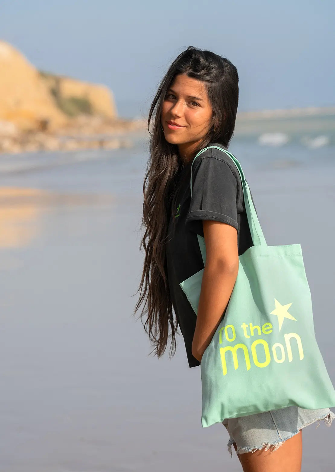 Tote Bag de lona en color verde agua de To the Moon con marca en color flúor.