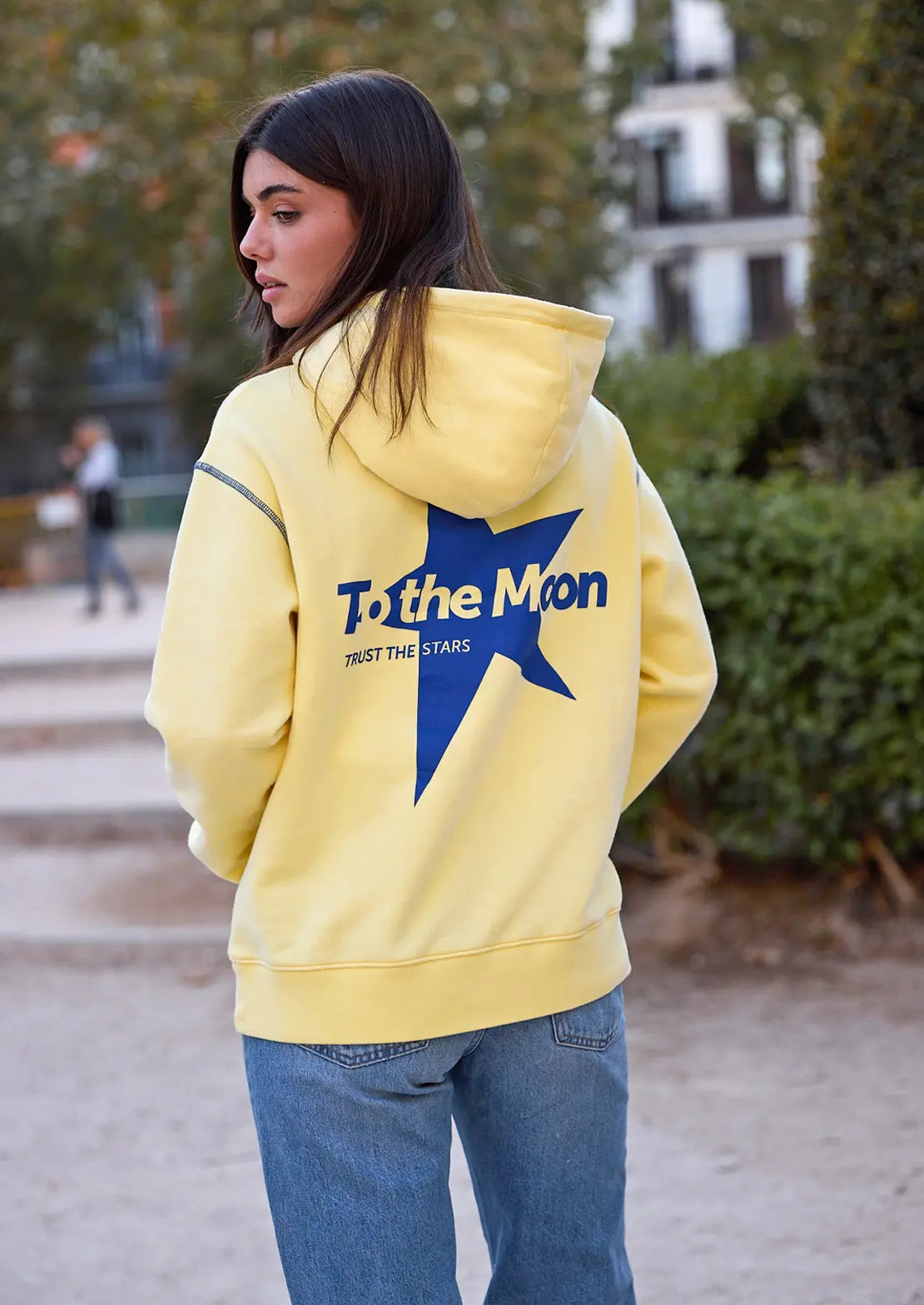 Hoodie de To the Moon en color amarillo claro con capucha y bolsillo canguro. Serigrafía azul eléctrico en la espalda estrella.
