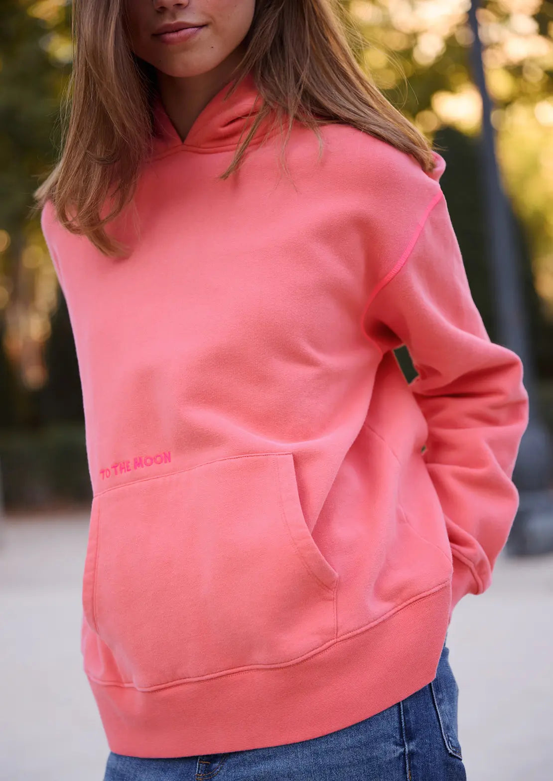 La hoodie con capucha color coral de la temporada con capucha y bolsillo canguro de To the Moon. Serigrafía fucsia flúor estrella y bordado de marca en parte delantera.
