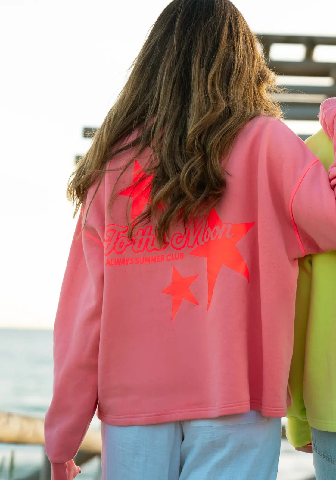 Sudadera Loose Sunset diseño con manga caída color coral con contrastes rubí flúor y estrellas flúor en la espalda.
