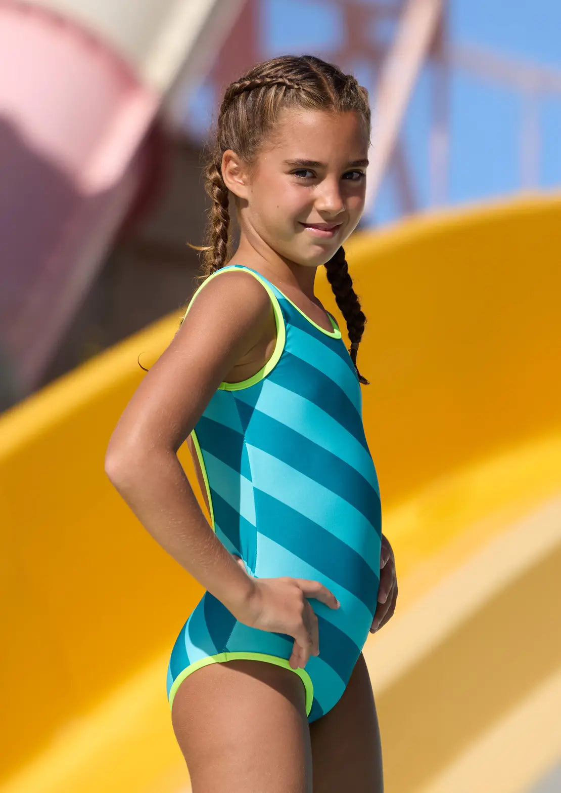 Traje de baño de niña y teen con estampado de rayas oblicuas en tonos azules con contrastes en amarillo flúor.

